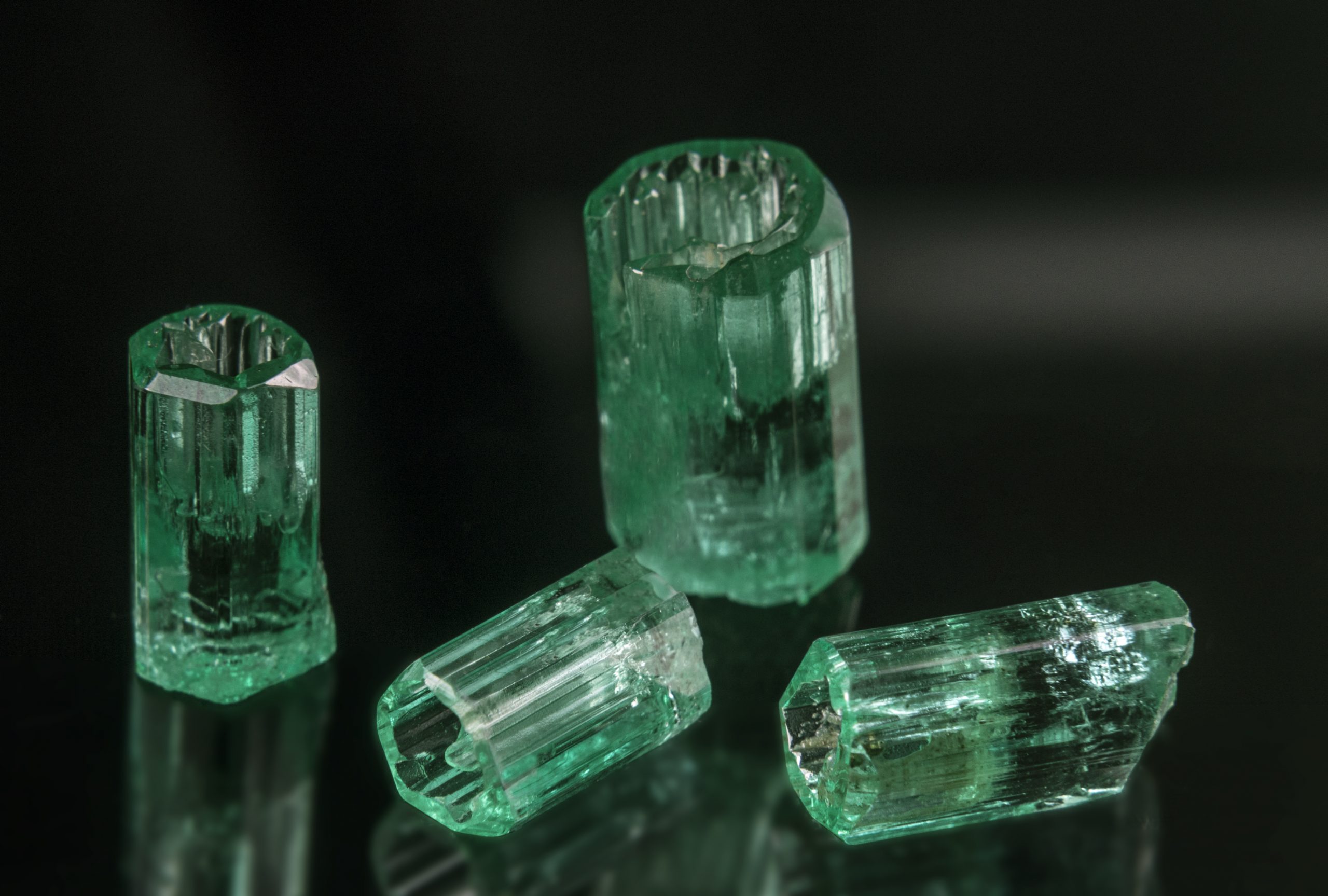 Quatre cristaux d’émeraude appelés localement vasos (verres), par analogie à la forme d’un verre miniature. District minier de Chivor, Colombie. Hauteur du cristal vertical : 12 mm. Collection du MIE. Photo : Yungger Gutiérrez-Camelo.