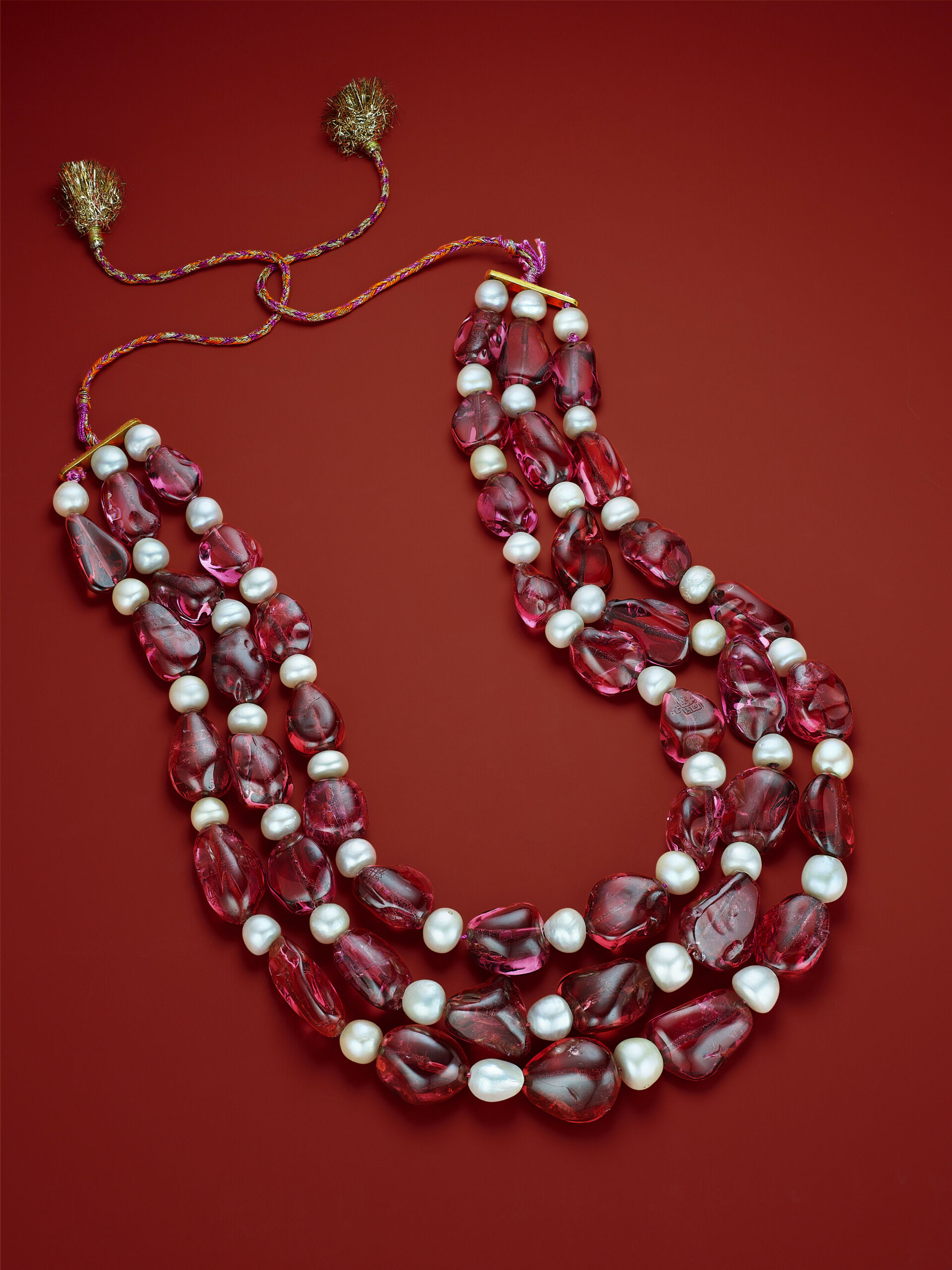 Three-strand Mughal necklace of pink spinels and natural pearls, composed of forty-five polished spinel beads, forty-eight natural saltwater pearls (rounded to near-round, approx. 13.20 mm to 9.90 mm in diameter), yellow gold, circa 1750, twisted cord in rose and gold thread, eight engraved spinels. SSEF, 2022, report no. 126236: Spinels from Tajikistan, no indications of heat treatment, with low to moderate oil in fissures at the time of testing; natural saltwater pearls, with additional letter. Lot 43. Christie’s New York, June, 17, 2025