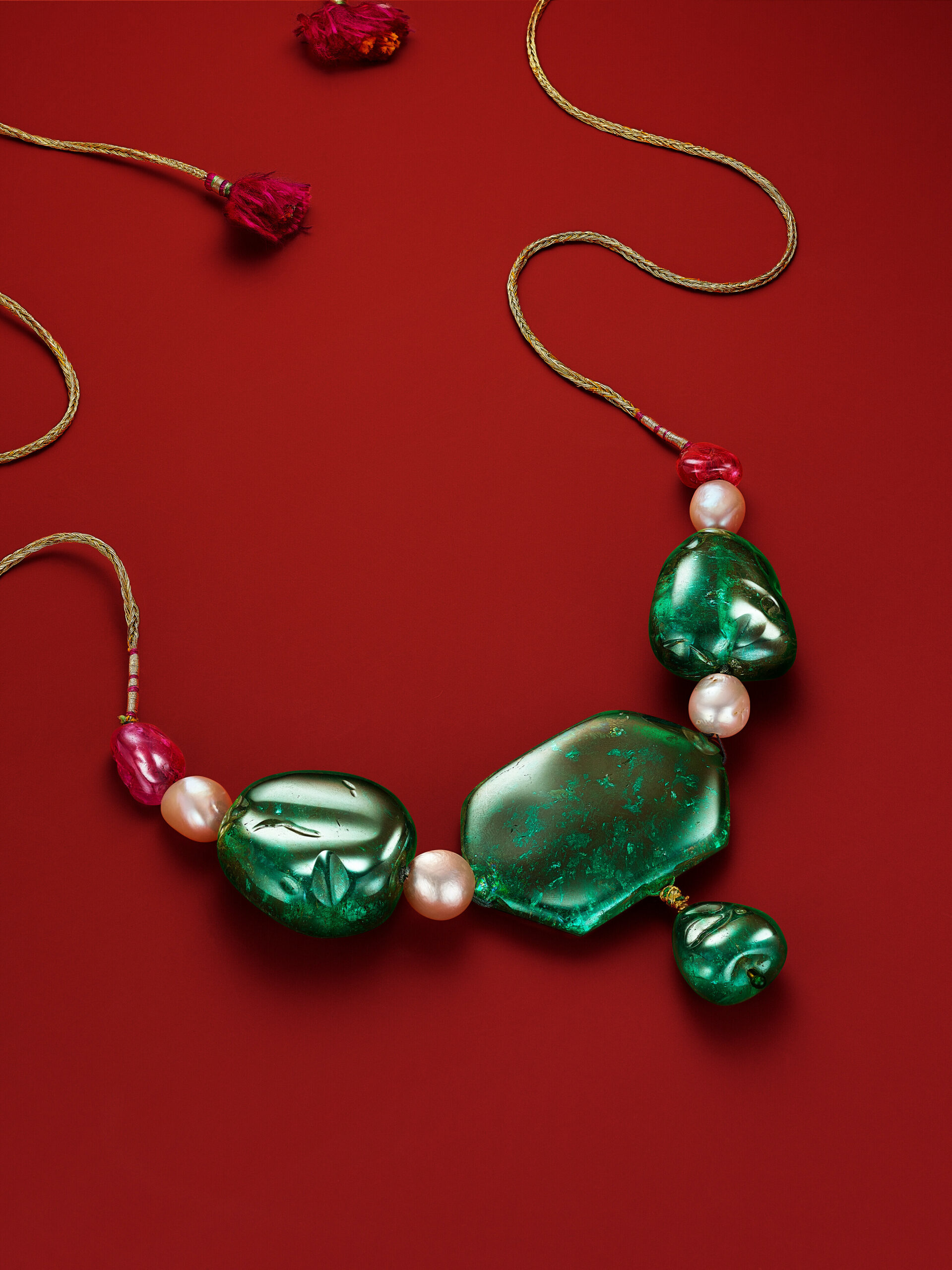 42 A MUGHAL MULTI-GEM AND EMERALD NECKLACE Centering upon a hexagonal and drop-shaped emerald of approximately 297.00 carats total, two baroque-shaped emeralds, baroque drop-shaped spinel bead, baroque ruby bead, baroque natural pearls of 14.20 to 11.60 mm, circa 1750, gold, later added magenta and green cord SSEF, 2022, report no. 126238: Emeralds: Colombia, indications of clarity modification, minor (E2) to moderate (E1, E3, E4) amount of oil in fissures at time of testing, Spinel: Tajikistan, no indications of heating, moderate amount of oil in fissures at the time of testing, Ruby: Burma, no indications of heating, minor amount of oil in fissures at the time of testing, Pearls: natural pearls, saltwater, with appendix letter regarding this Exceptional Emerald Strand Size/Dimensions: spinel to ruby panel 22.8 cm (9 in); cord 53.3 cm (21 in) Gross Weight: 163.2 grams $2,000,000-3,000,000 SHOULD YOU WISH TO BID ON THIS LOT, YOU WILL BE REQUIRED TO OBTAIN A HIGH VALUE PADDLE. Please note the emeralds strung on either side of the center panel weigh approximately 255.00 and 246.00 carats.